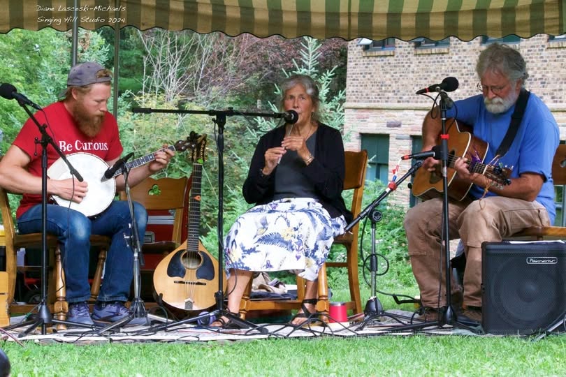 Celtic trio performing with banjo, flute, and guitar on the Glen grounds